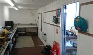 internal view of converted office shipping container. ply lined along the walls and ceiling with workbenches