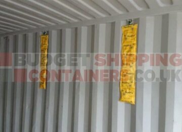 Interior of a shipping container. Lining the walls are long strips of yellow packets.