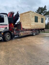 Cladded shipping container on the back of a hiab truck