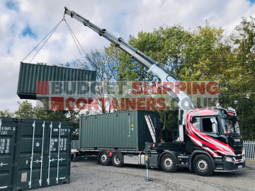 Hiab truck offloading a green shipping container via a crane