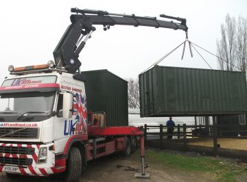 Truck lifting off a green 20ft shipping container